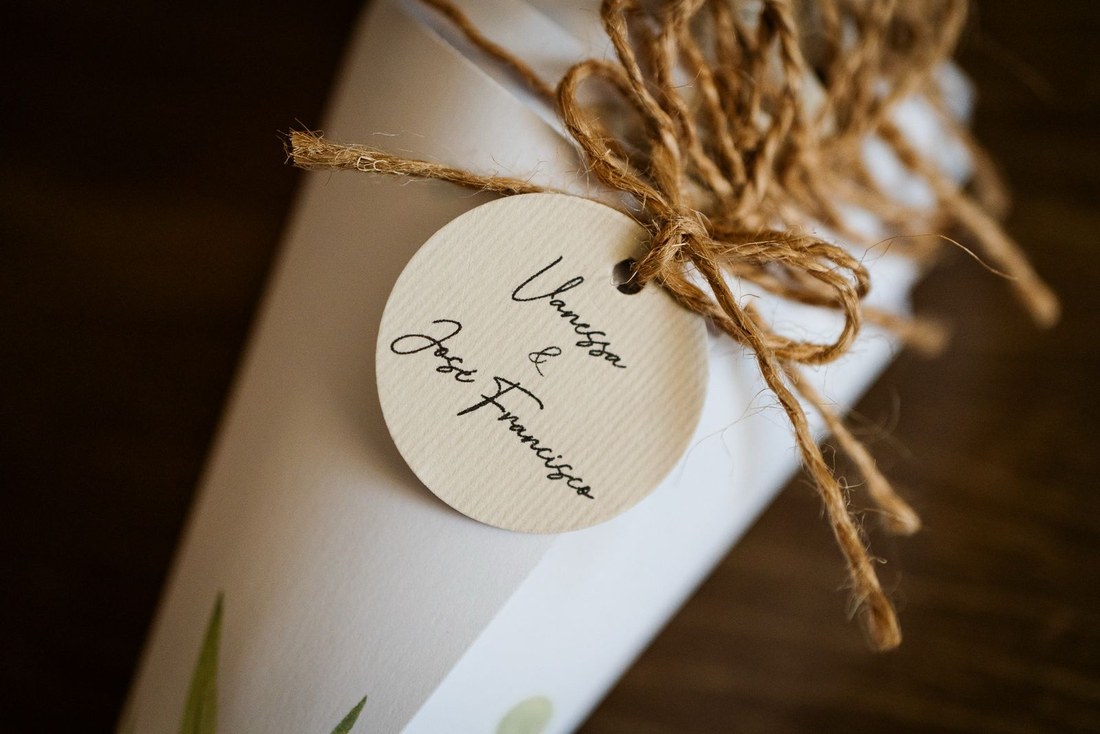 Cono para pétalos con una tarjeta redonda con los nombres de los novios, atada con cáñamo